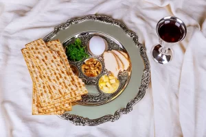 Passover seder plate with horse radish, boiled egg, unleavened bread, matzah, and apples.